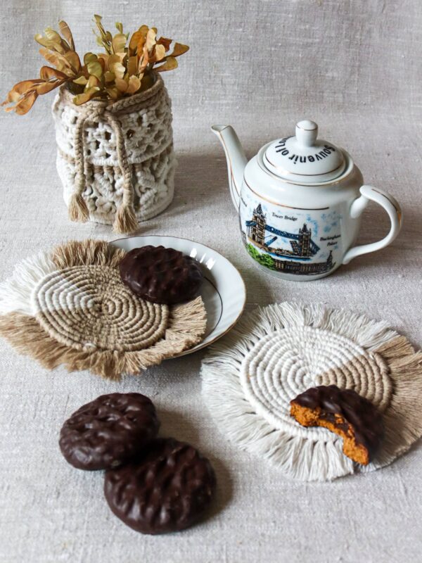 Okrągłe podkładki z pierniczkami i dzbankiem herbaty oraz makramowym wazonikiem z suszkami